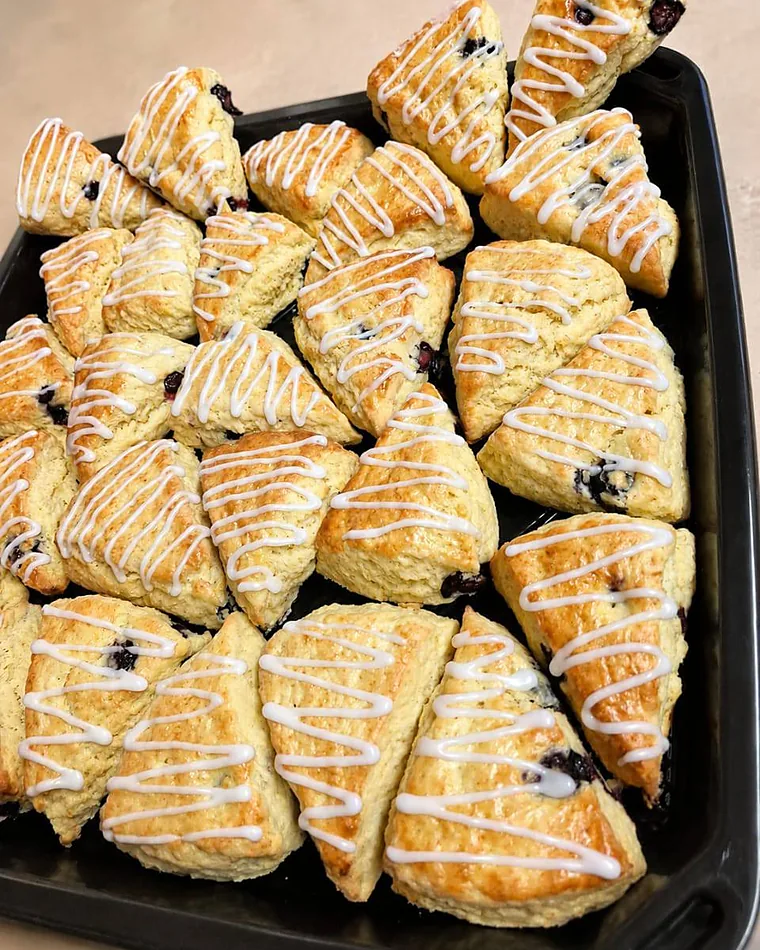 A tray of blueberry scones finished with a white icing drizzle